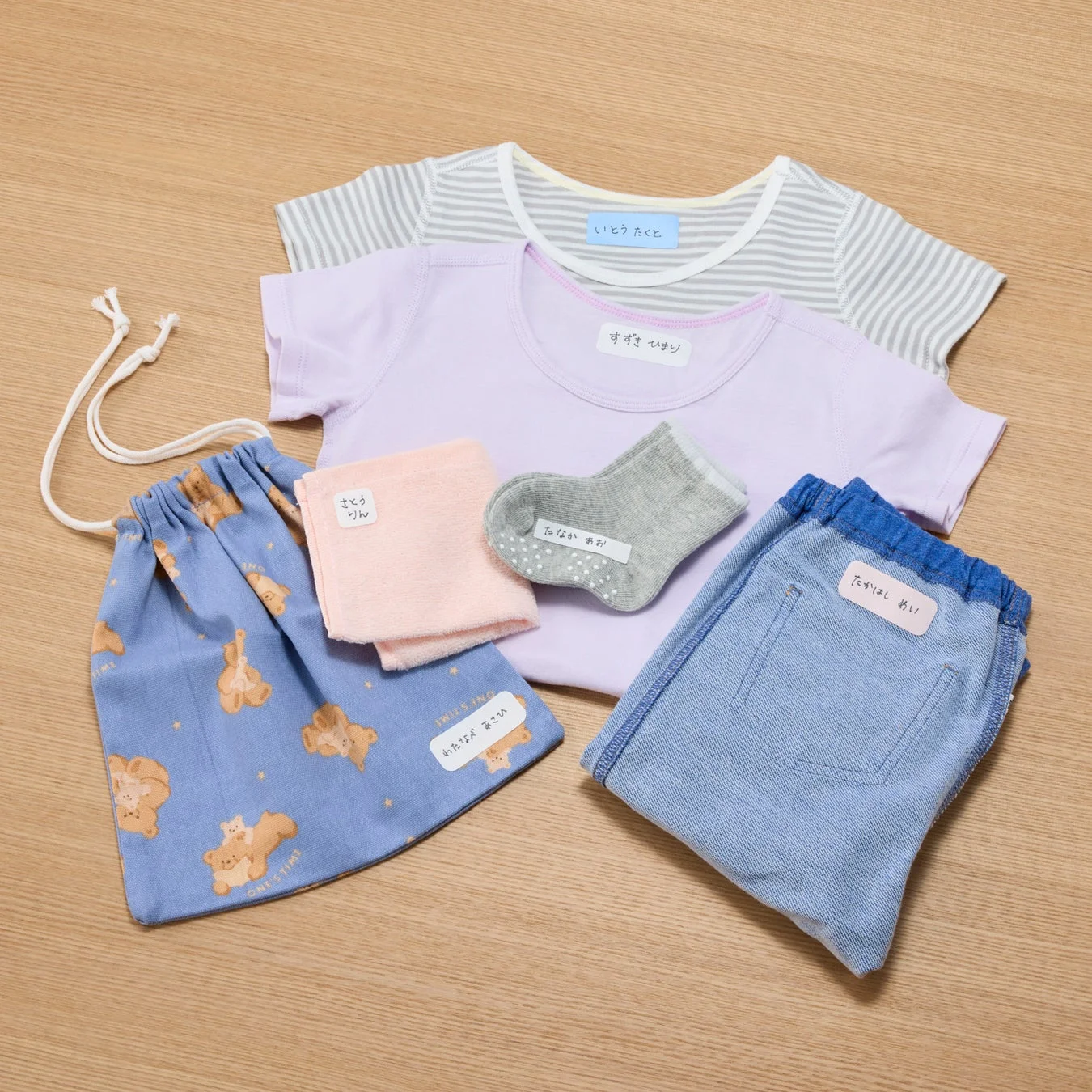 木製床に名前シールが貼られた子供服や小物