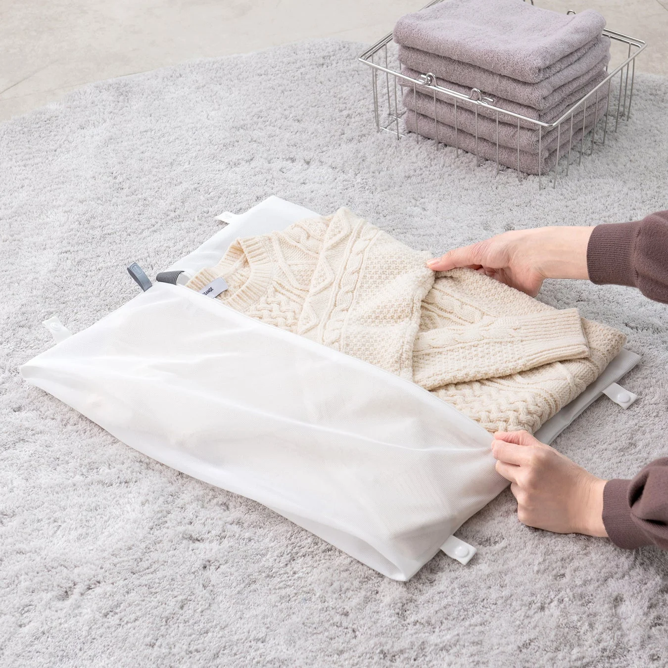クリーム色のセーターを白い洗濯ネットに入れている様子